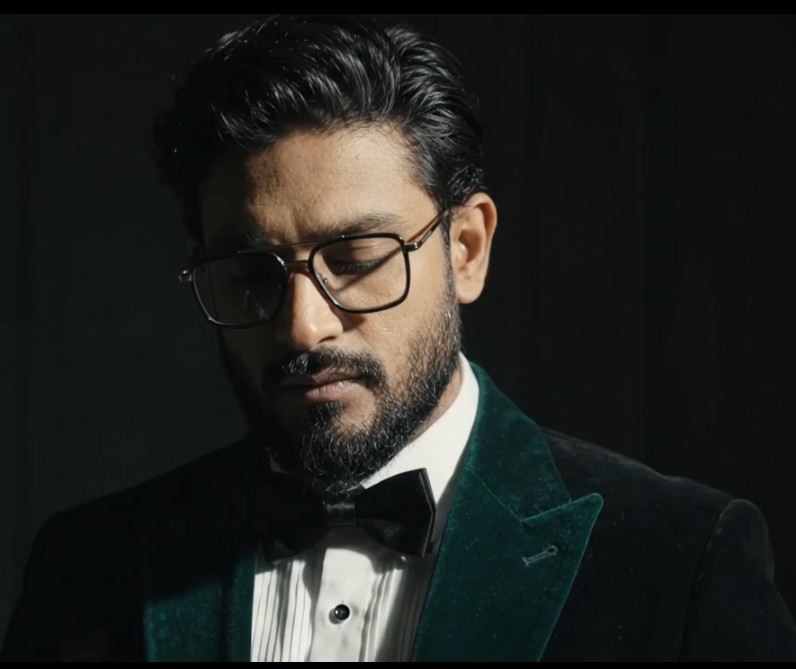 Habib Rahaman in a dark green velvet tuxedo, lit by a single cinematic key light